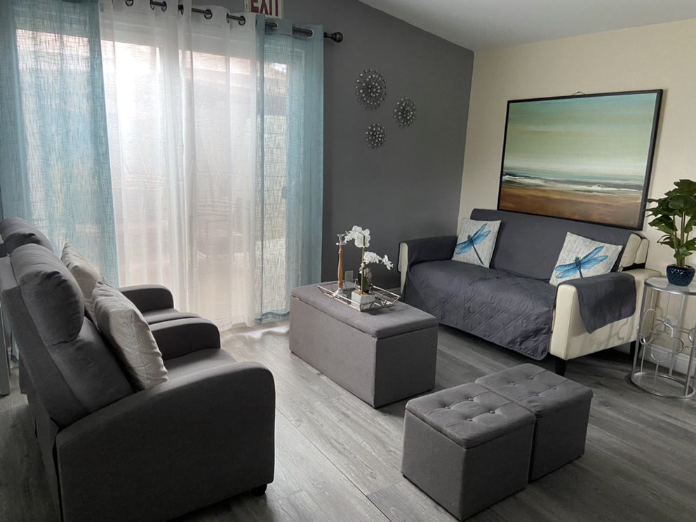 A modern, minimalist living room with a gray color scheme featuring a sofa, coffee table, and decorative elements.