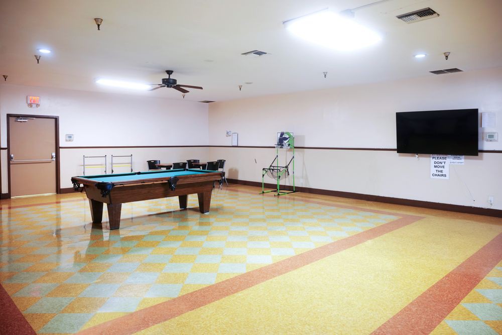 A spacious game room featuring a pool table and a wall-mounted television.