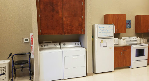 A laundry area featuring a washer and dryer with storage cabinets above, next to a refrigerator.