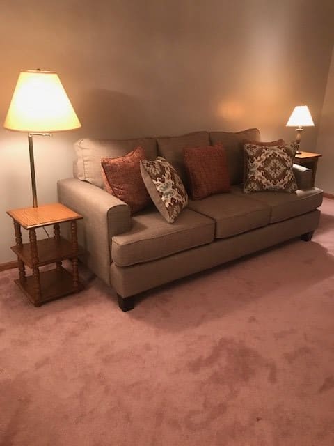 A cozy living room with a sofa, lamps, and decorative cushions.