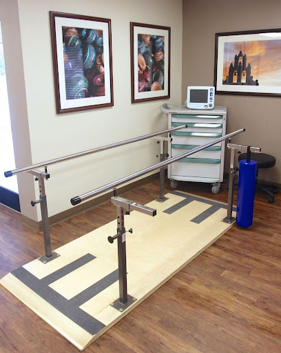 A physical therapy room featuring parallel bars for rehabilitation exercises.