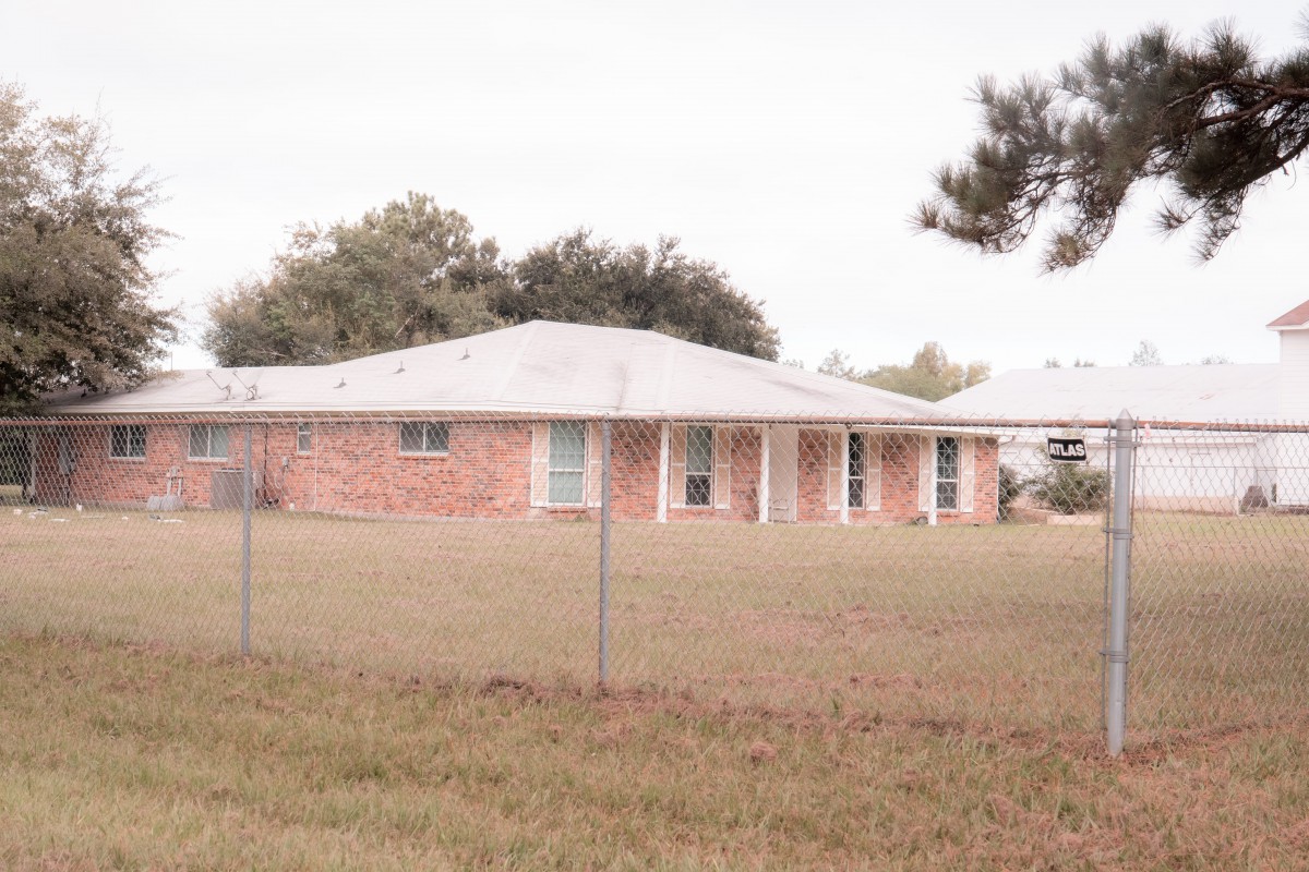A brick house with a fenced yard in a suburban area.