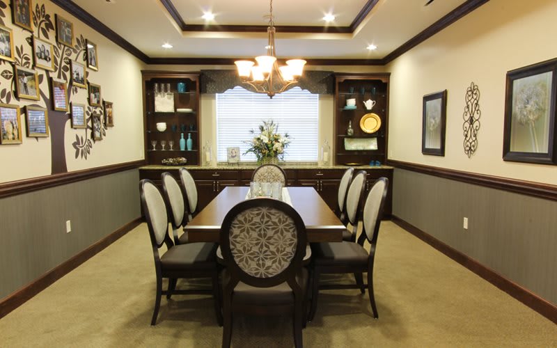 An elegantly designed dining room with a central table and six upholstered chairs, complemented by ambient lighting and tasteful decorations.