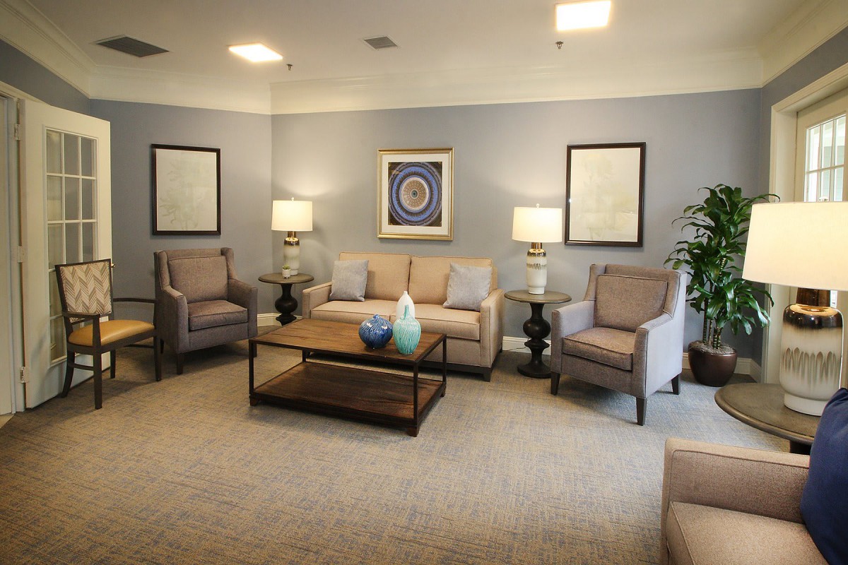 A cozy living room with a sofa, armchairs, and a coffee table, complemented by soft lighting and tasteful artwork.
