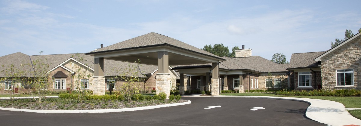 A modern building entrance with a covered driveway and landscaped surroundings.