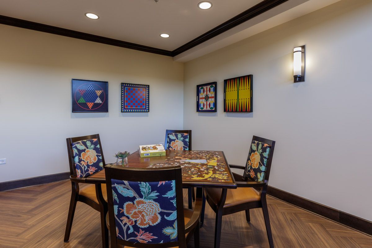 A cozy dining area with a beautifully set table surrounded by floral-patterned chairs, adorned with vibrant artwork on the walls.