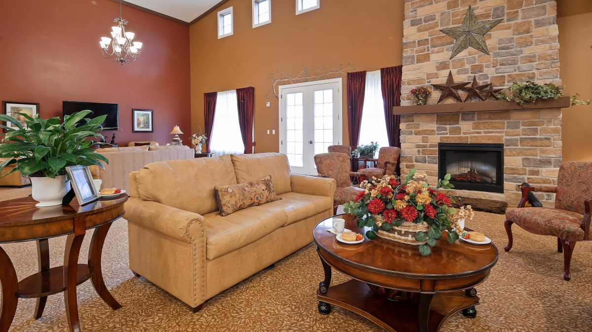 A cozy living room with a beige sofa, a wooden coffee table with floral decor, and a stone fireplace.