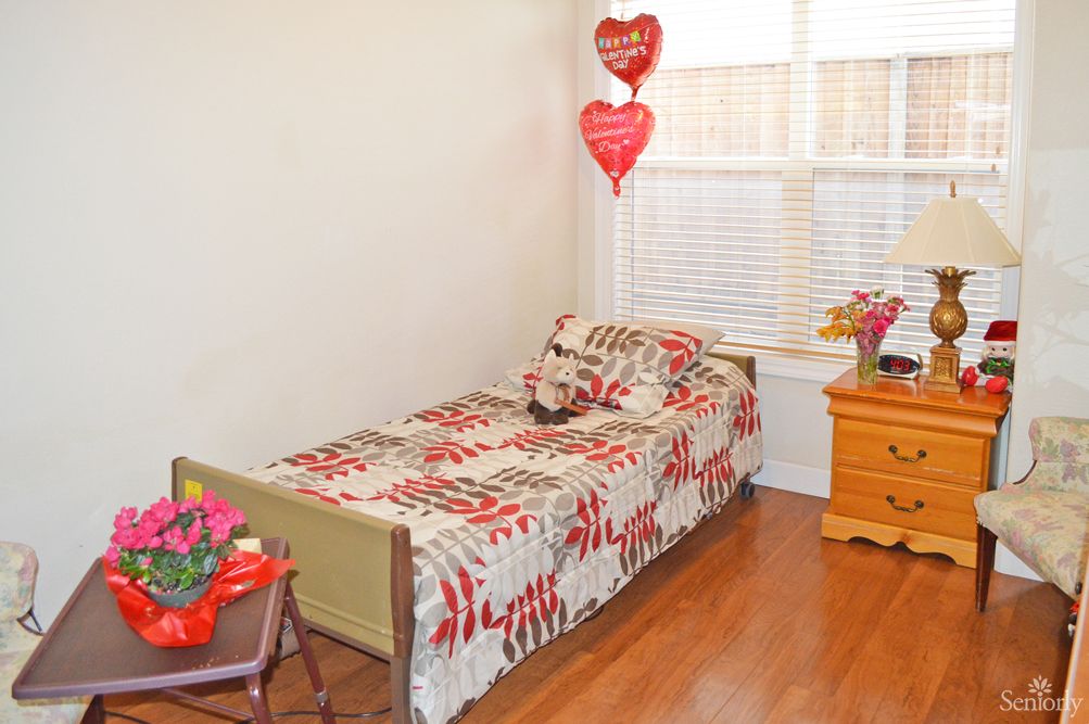 A cozy bedroom with a single bed, featuring floral bedding and heart-shaped decorations.