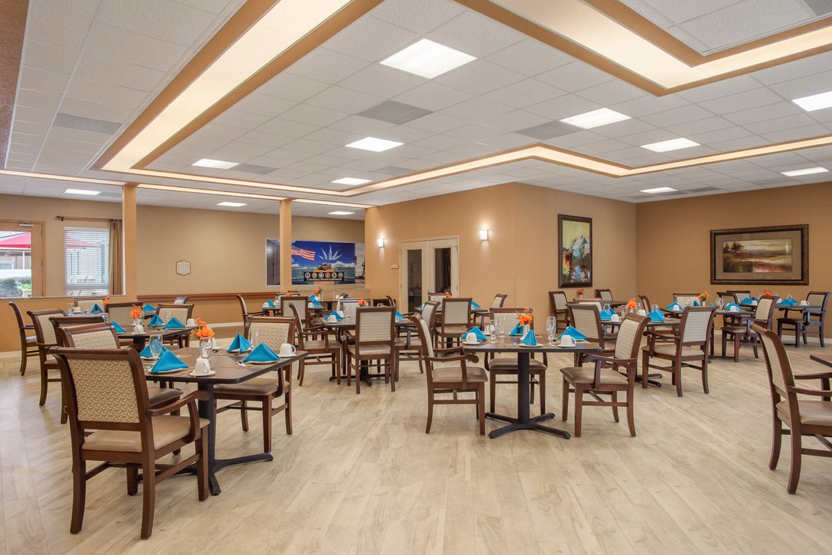 An elegant dining room setup with multiple tables and chairs arranged neatly under warm lighting.