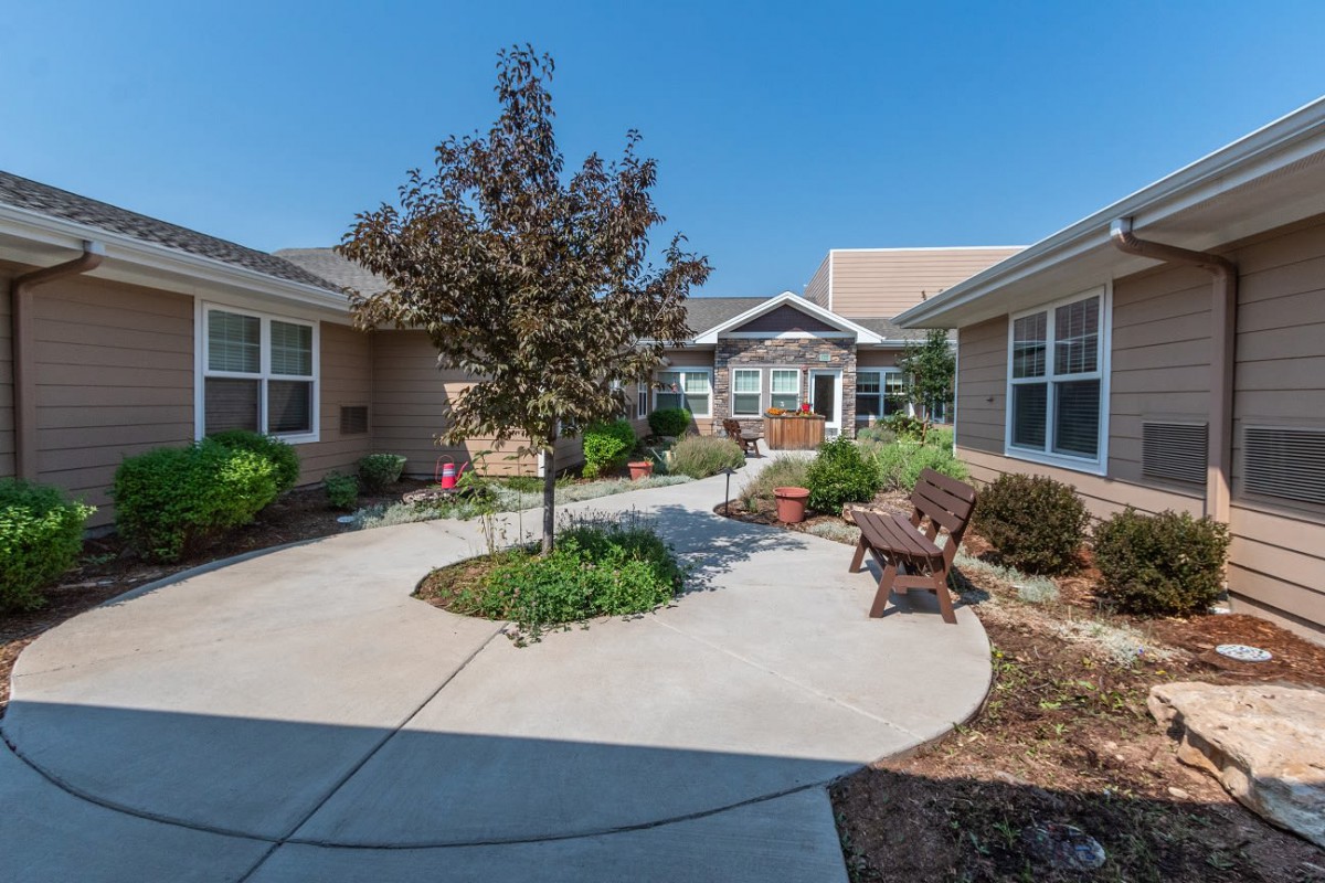 A peaceful courtyard with a central tree, surrounded by benches and landscaped gardens.