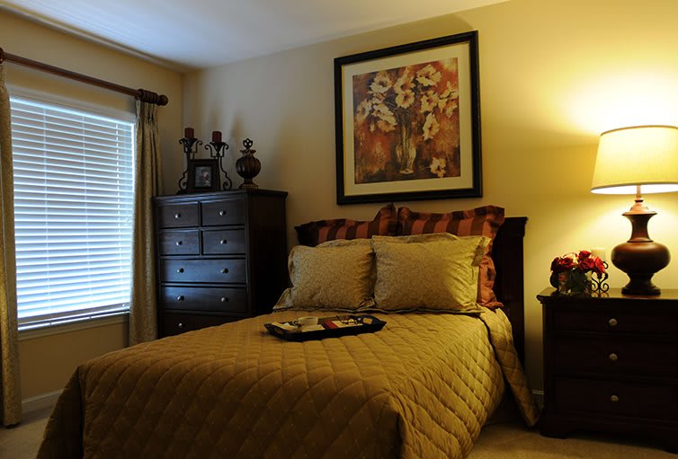 A cozy bedroom with elegant interior design, featuring a single bed, framed artwork on the wall, and warm lighting.