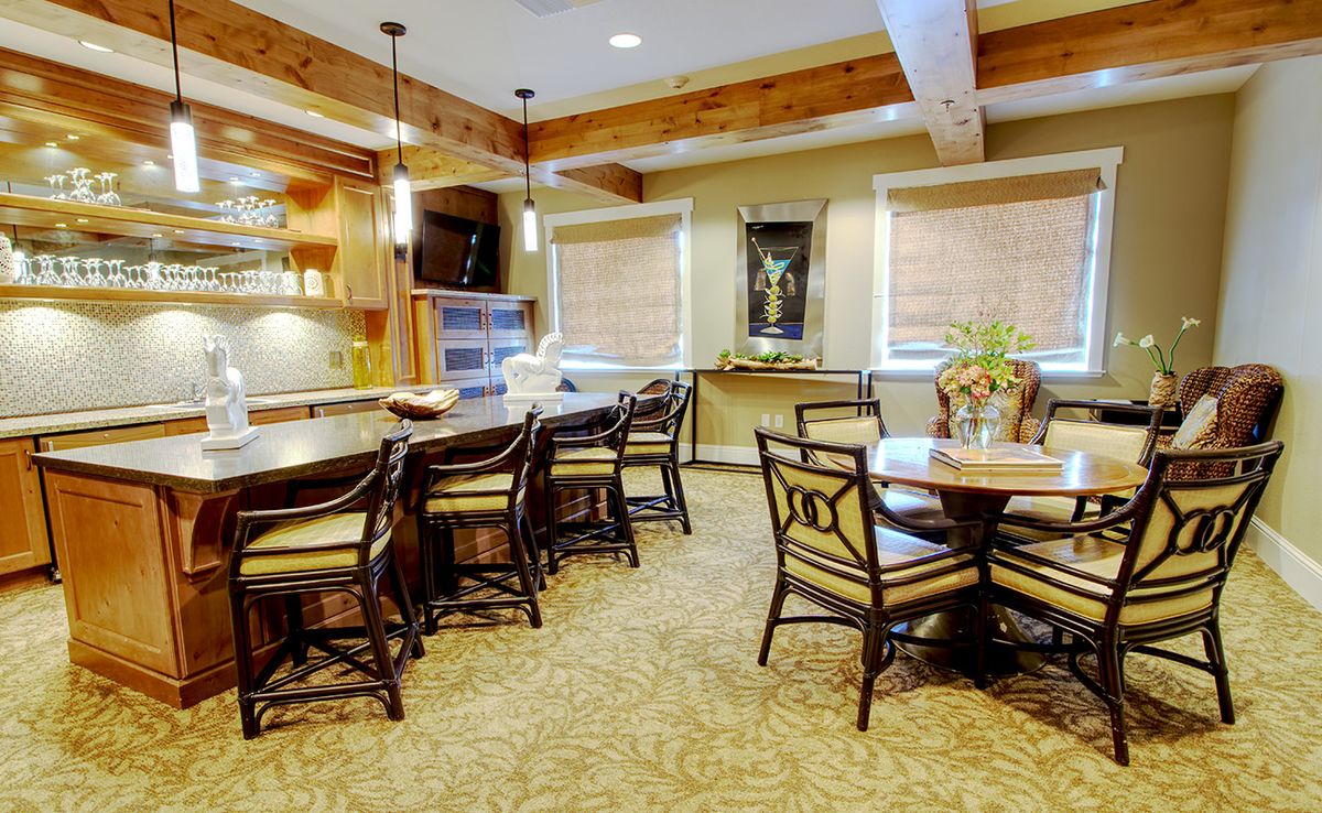 A cozy kitchen and dining area with wooden beams, elegant chairs, and warm lighting.