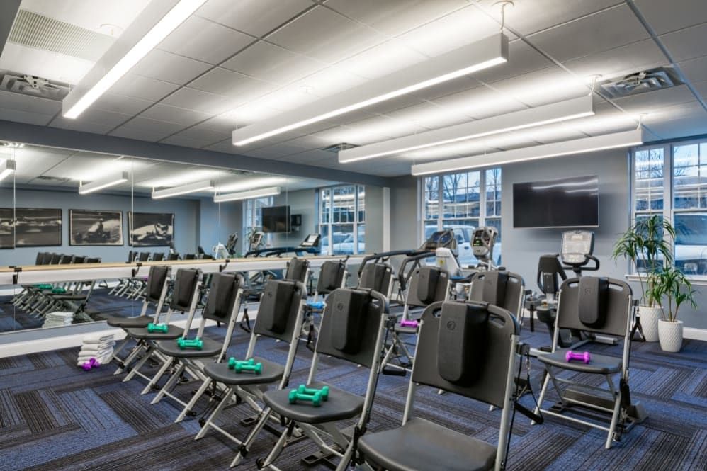 A well-lit gym with exercise equipment and chairs set up for a fitness class.