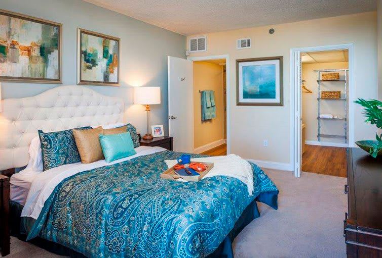 A modern bedroom featuring elegant decor, vibrant bedding, and stylish artwork.