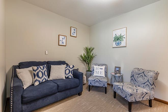A cozy living room with a navy sofa, patterned chairs, and decorative artwork on the walls.