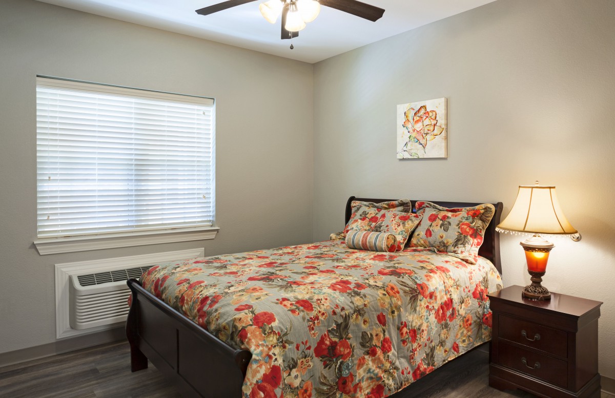 A cozy bedroom with floral bedding and a ceiling fan.
