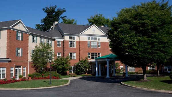 A residential brick building with a driveway and landscaped surroundings.