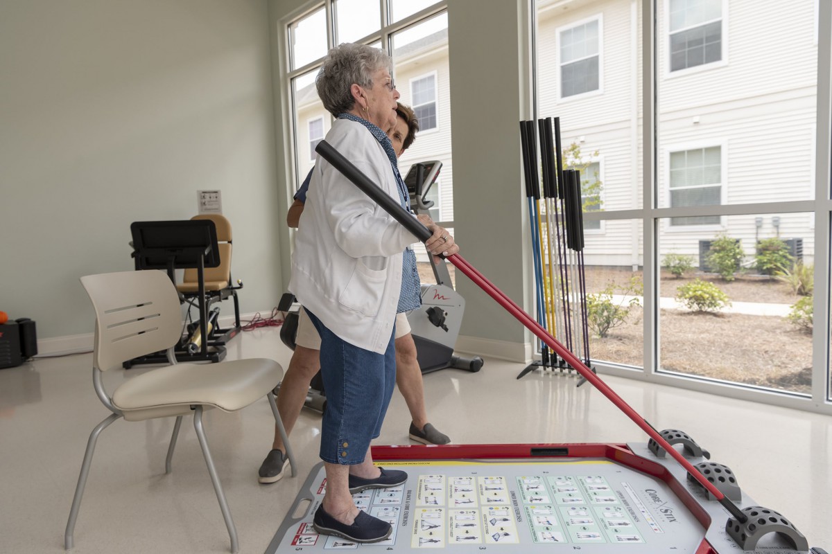 An elderly woman participates in a game of shuffleboard at a community center.