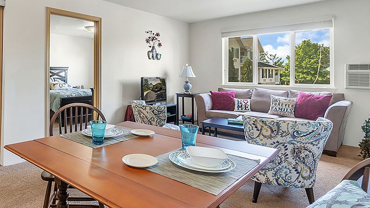A cozy living room with an adjacent dining area, featuring a set table and comfortable seating.