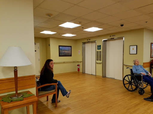 A woman sitting in a hospital waiting area next to a wheelchair.