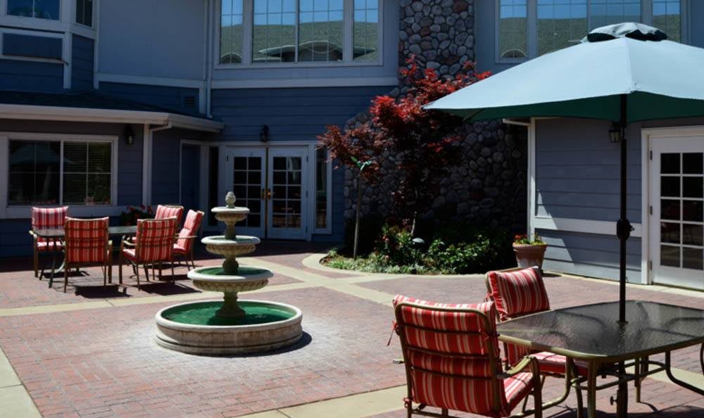 A peaceful courtyard with a central fountain and outdoor seating surrounded by a building.