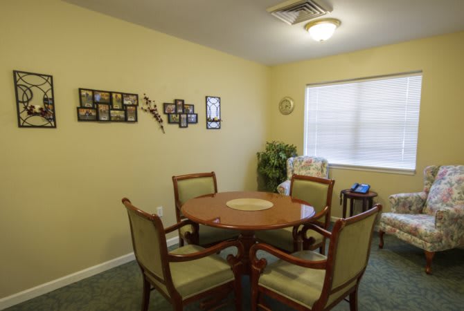 Cozy dining area with a round table and four chairs, featuring wall decor and a window providing natural light.