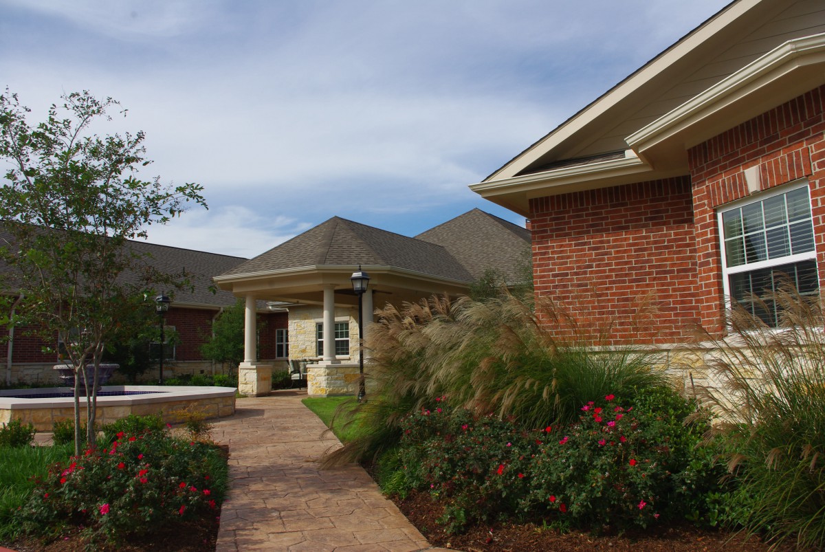 A red brick house with a landscaped garden and a pathway leading to the front entrance.
