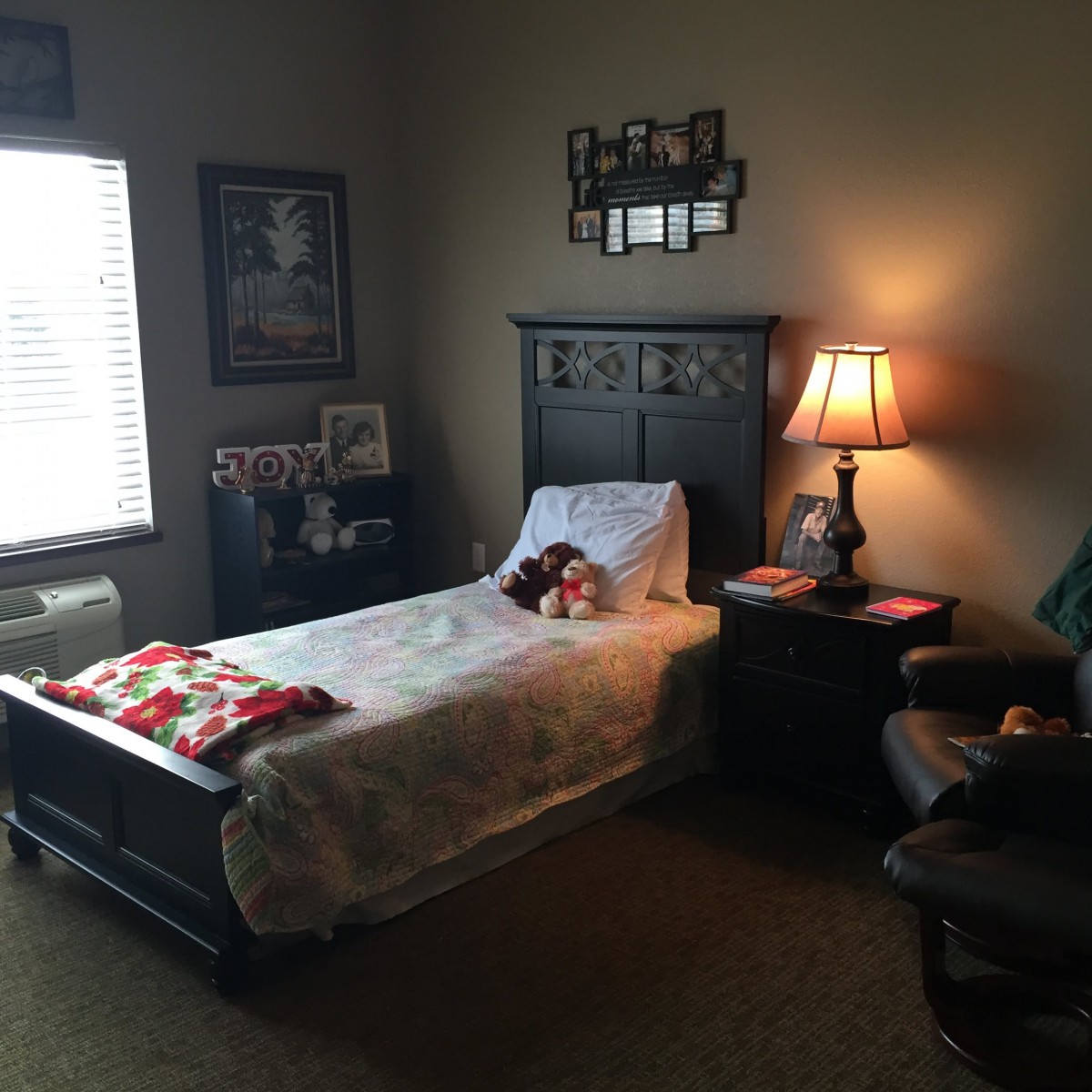 A cozy bedroom with a single bed, lamp, nightstand, and chair.