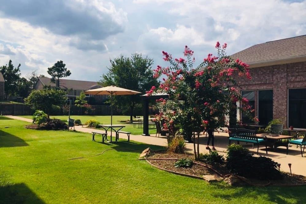 A beautiful garden with lush greenery, a patio, and blooming flowers.