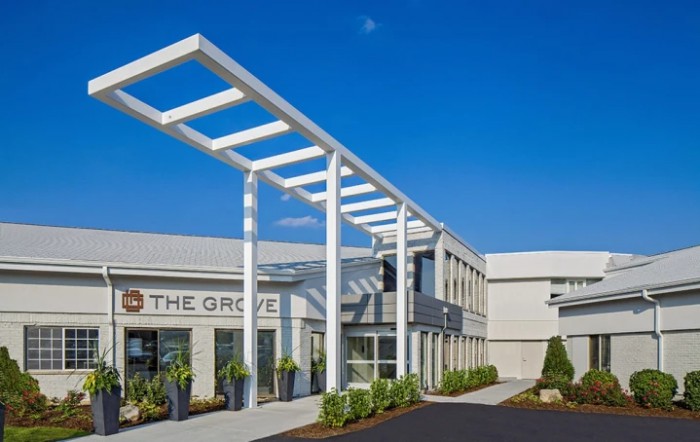 The entrance of a modern commercial building under a clear blue sky.