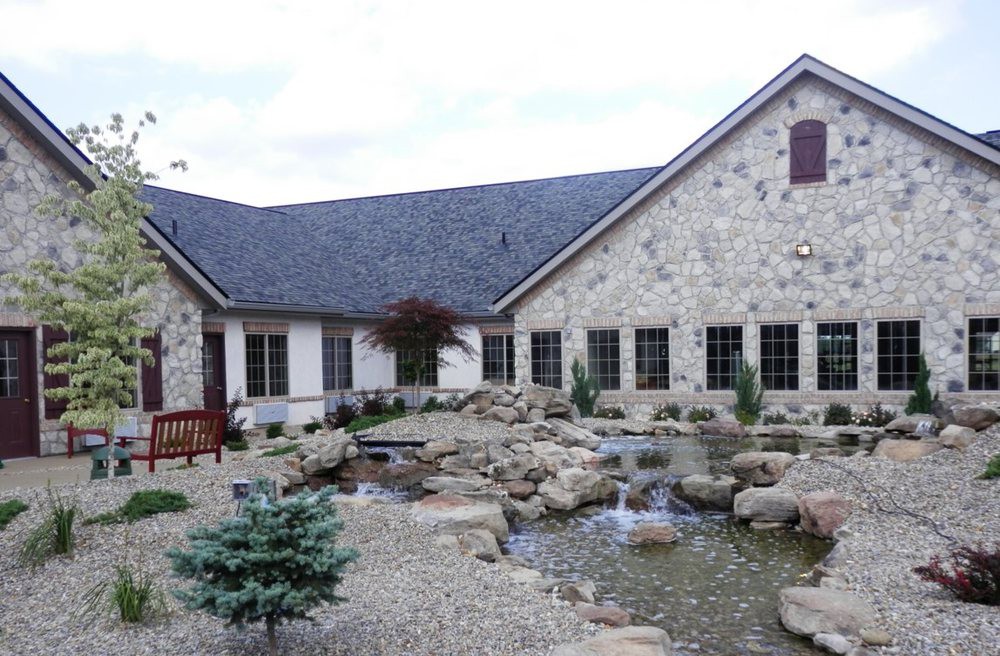 A stone building with a beautifully landscaped garden featuring a pond and rocks.