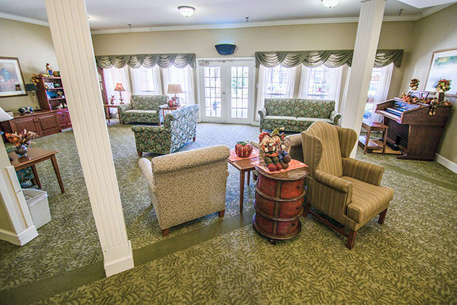 A cozy living room with multiple seating areas and large windows.