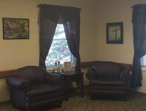 A cozy living room setup featuring two chairs, a small table, and window curtains.