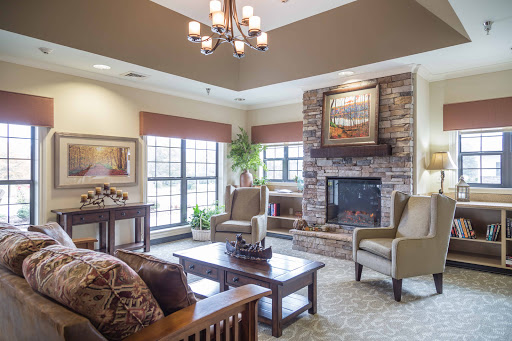 A cozy living room featuring a stone fireplace, comfortable seating, and ample natural light.