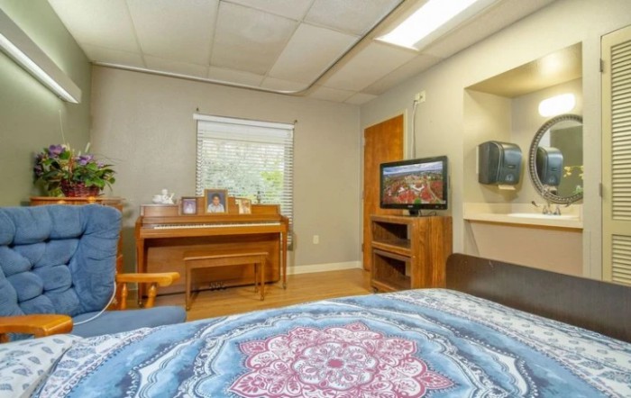 A cozy room with a piano, television, and a bed.