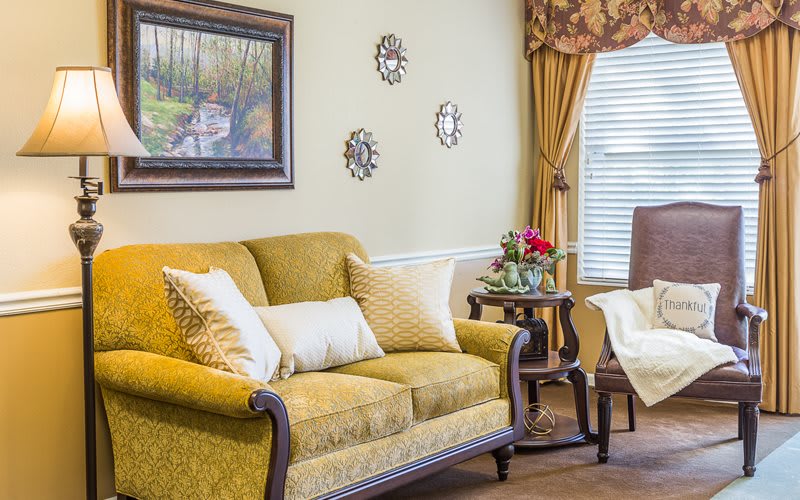 A cozy living room with a yellow sofa, decorative pillows, and elegant wall art.