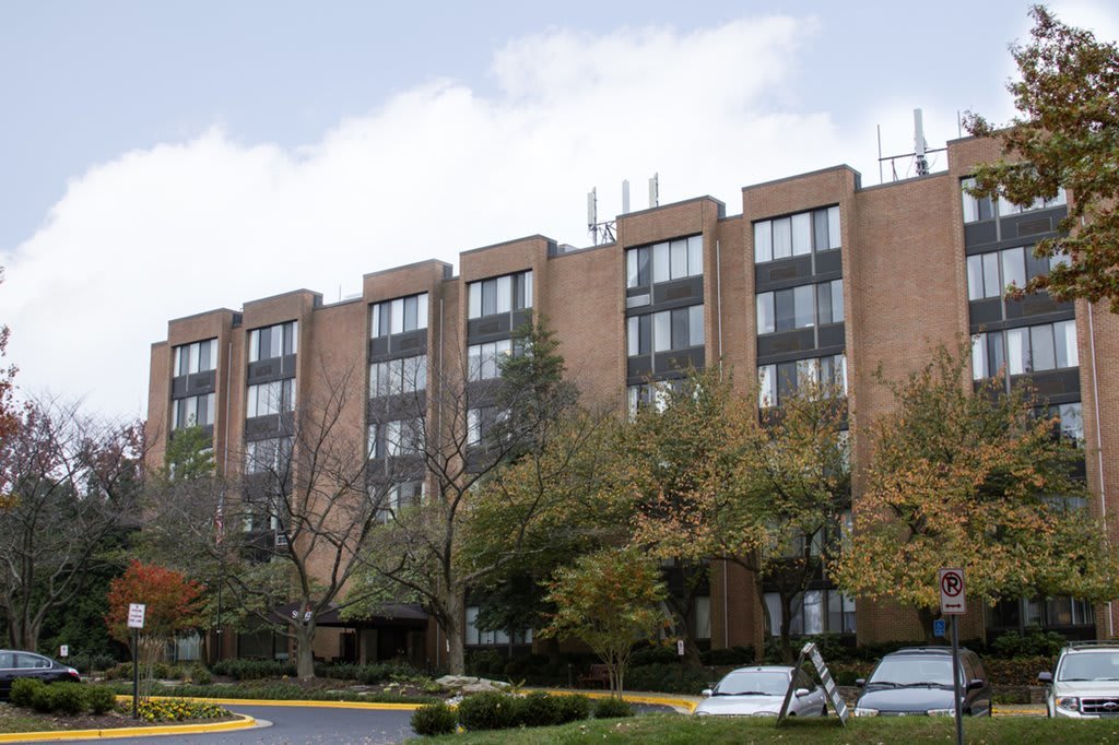A residential apartment building with trees and parked cars in front.