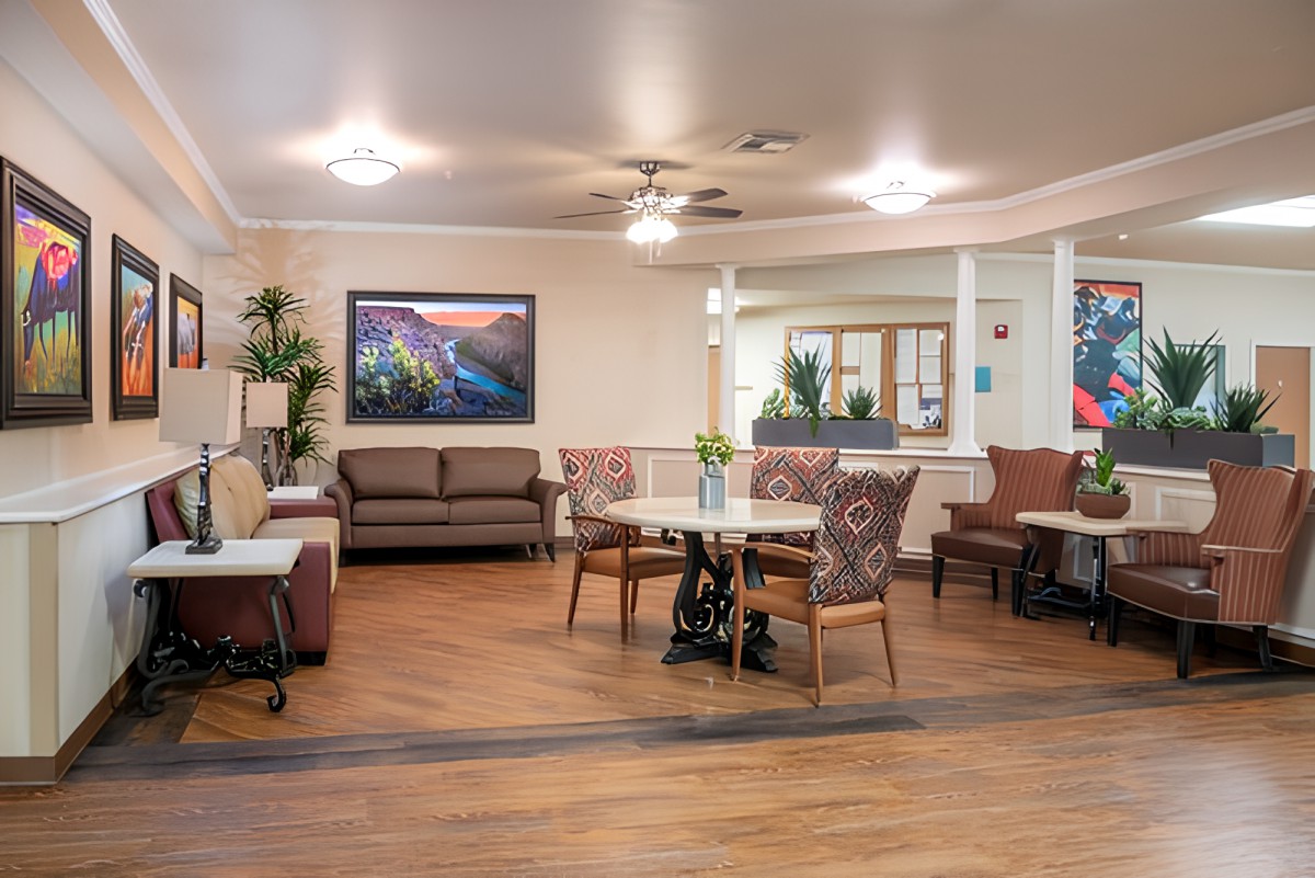 A cozy and well-lit seating area with tables, chairs, and a sofa in an interior space.