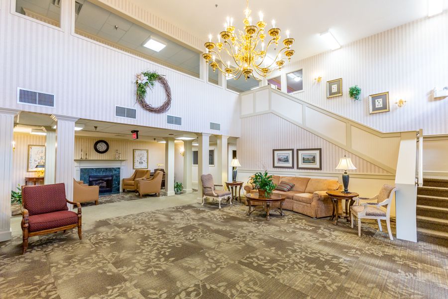 A spacious lobby with elegant furnishings and a grand chandelier, featuring a cozy seating area and decorative elements.