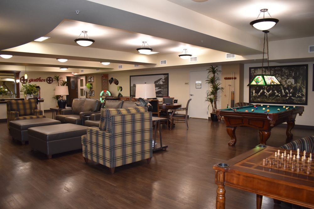 A spacious and well-furnished lounge area featuring sofas, chairs, and a pool table.