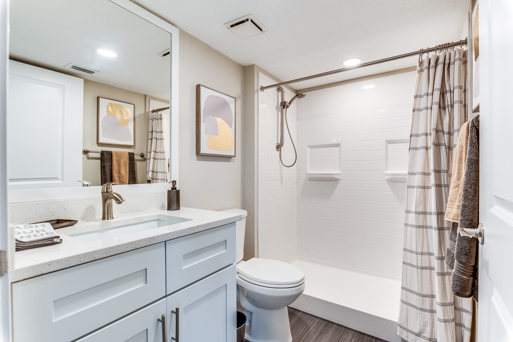 A modern and minimalist bathroom with a shower, sink, and toilet.