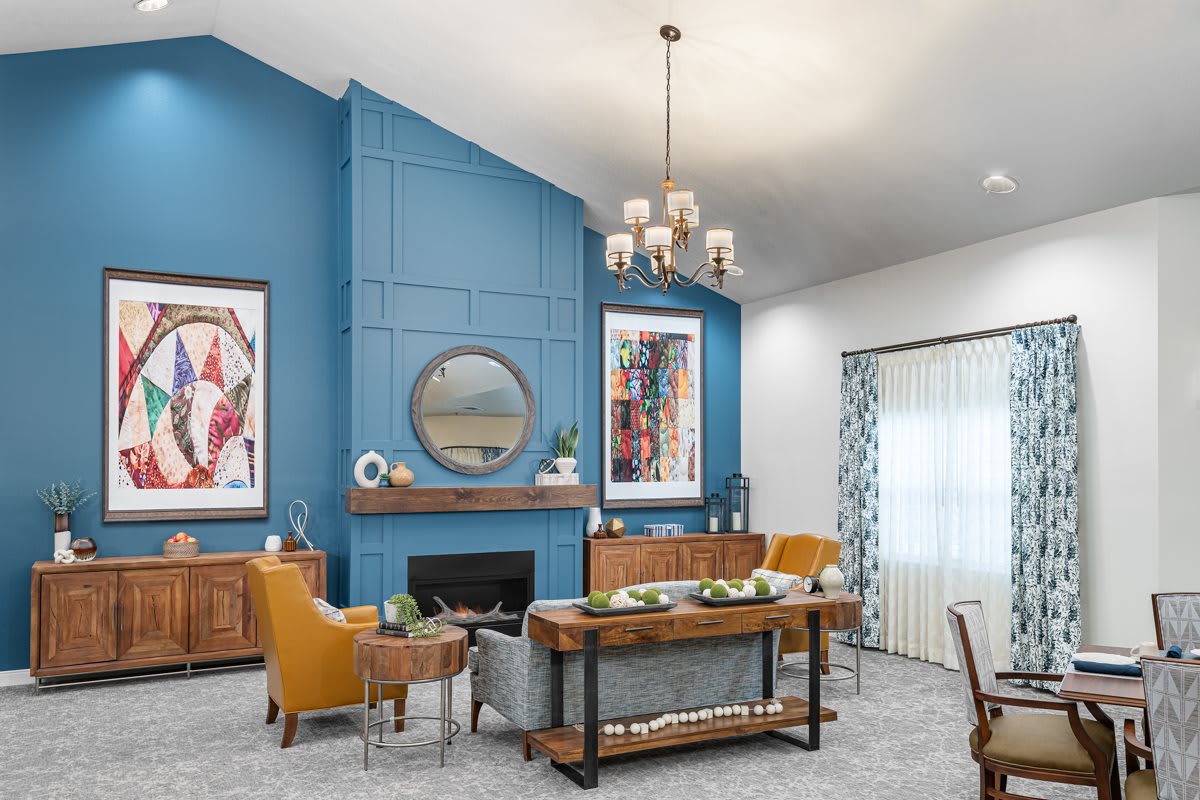A modern living room featuring a bold blue accent wall, stylish chandelier, and contemporary furniture.