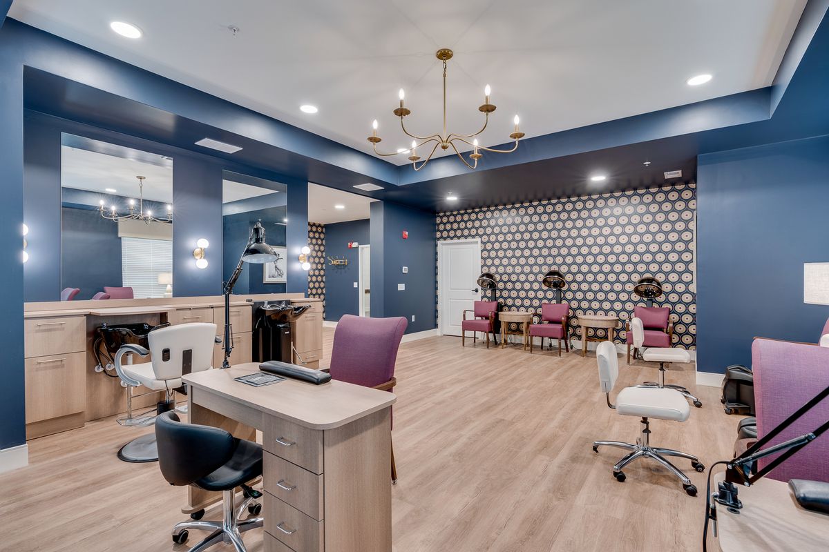 A stylish beauty salon interior with modern decor and a central chandelier.