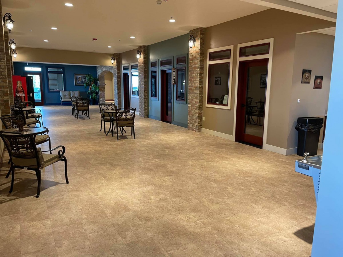A spacious and well-lit lobby with modern decor, featuring several seating areas with tables and chairs.