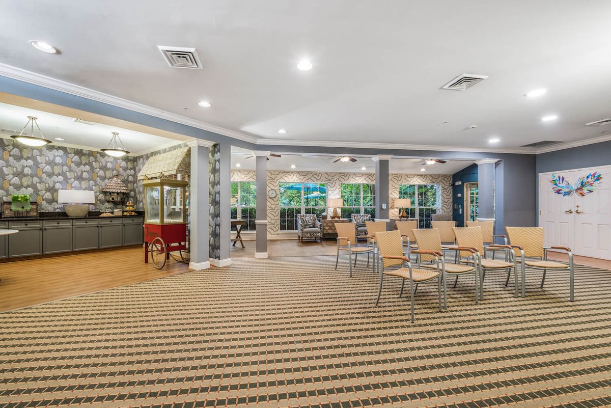 A spacious meeting room with rows of chairs, a popcorn machine, and large windows allowing natural light.