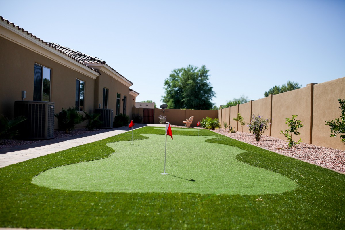 A residential backyard featuring an artificial turf putting green.