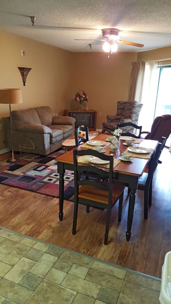 A cozy dining area with a table set for a meal, adjacent to a comfortable living space with sofas and a lamp.