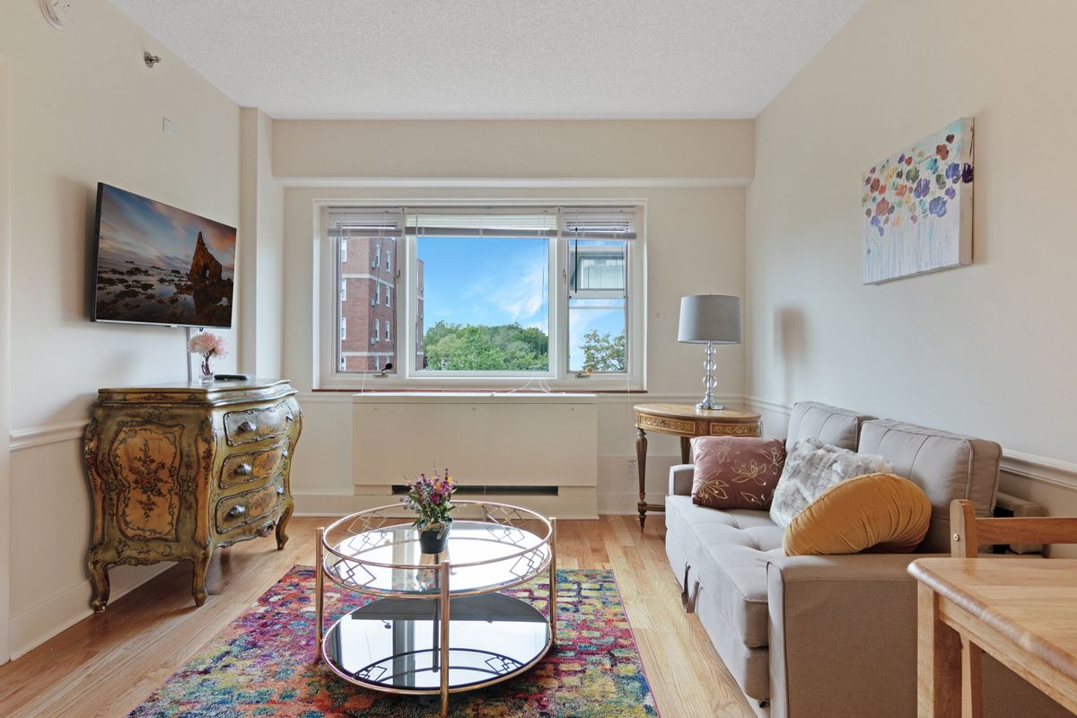 A cozy living room with a large window, comfortable sofa, and colorful rug.