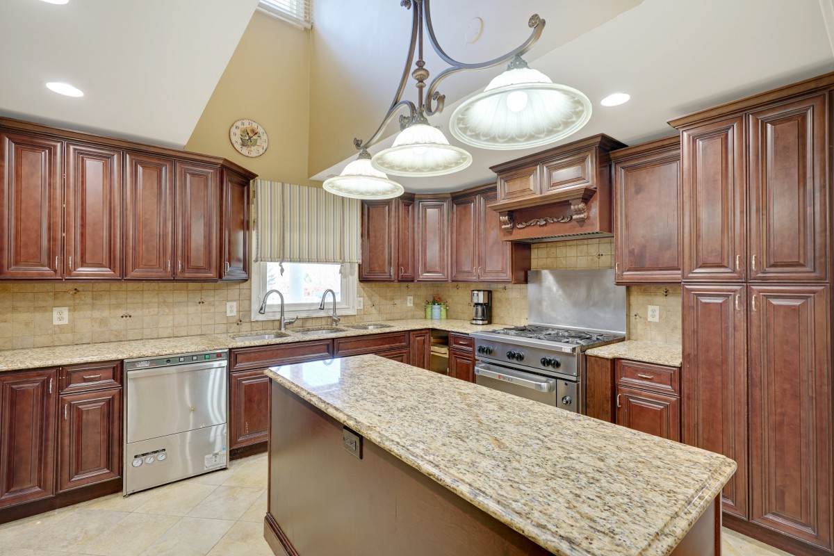 A modern kitchen with wooden cabinets, granite countertops, and stainless steel appliances.