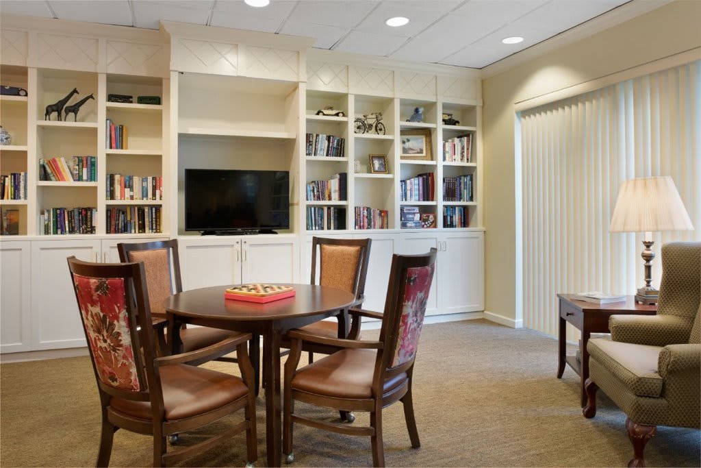 A cozy living room with bookshelves, a table, chairs, and a television.